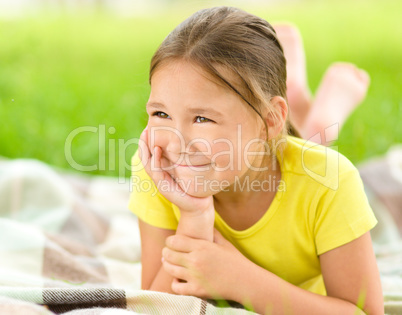 Portrait of a little girl laying on green grass