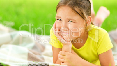 Portrait of a little girl laying on green grass