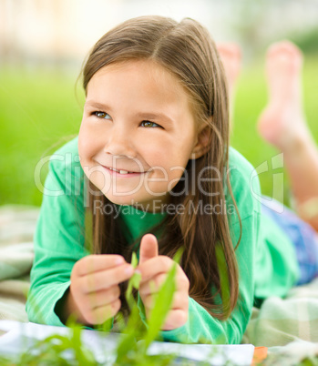 Portrait of a little girl laying on green grass