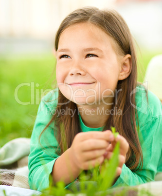 Portrait of a little girl laying on green grass