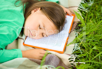 Girl is sleeping on her book outdoors