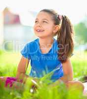 Portrait of a little girl sitting on green grass