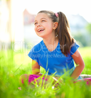 Portrait of a little girl sitting on green grass