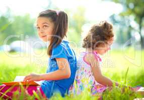 Two little girls are reading books