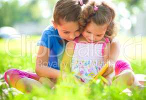 Two little girls are reading book