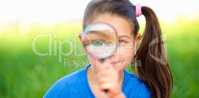 Little girl is looking through magnifier