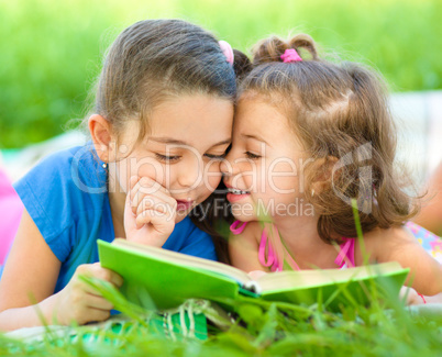 Two little girls are reading book