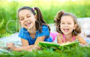 Two little girls are reading book