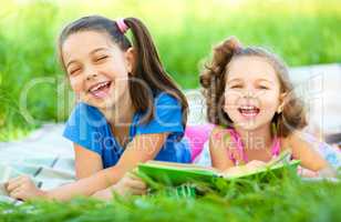 Two little girls are reading book