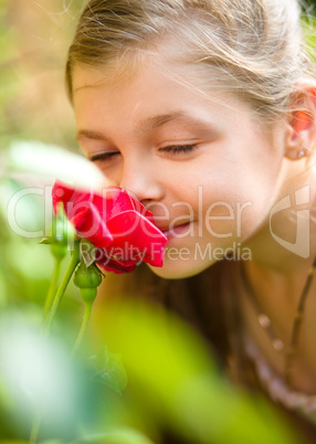 Portrait of a cute little girl smelling rose