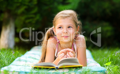 Little girl is reading a book outdoors Little girl is reading a book outdoors