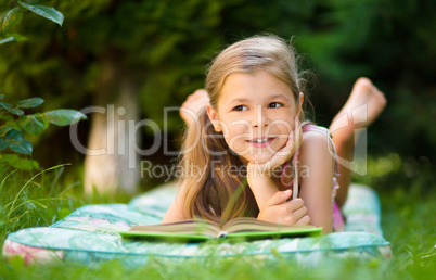 Little girl is reading a book outdoors Little girl is reading a book outdoors