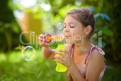 Little girl is blowing a soap bubbles