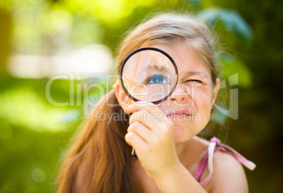 Little girl is looking through magnifier