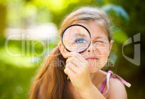 Little girl is looking through magnifier