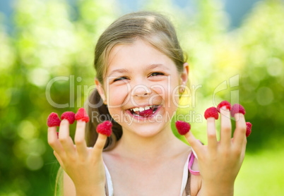 Young girl is holding raspberries on her fingers