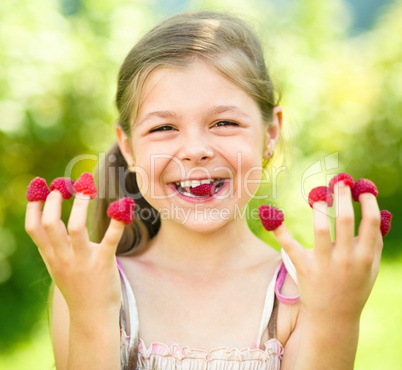 Young girl is holding raspberries on her fingers