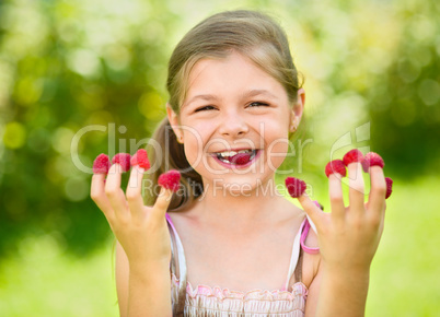 Young girl is holding raspberries on her fingers