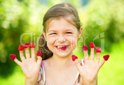 Young girl is holding raspberries on her fingers