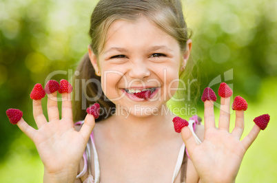 Young girl is holding raspberries on her fingers