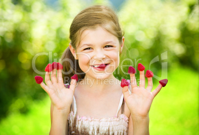 Young girl is holding raspberries on her fingers