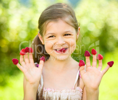 Young girl is holding raspberries on her fingers