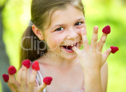 Young girl is holding raspberries on her fingers