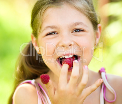 Young girl is holding raspberries on her fingers