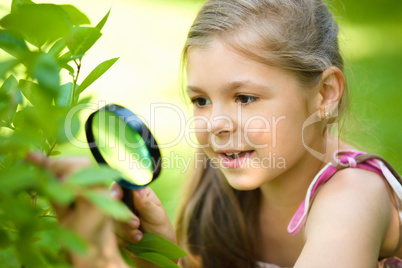 Girl is looking at tree leaves through magnifier