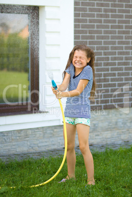 Happy girl pouring water from a hose
