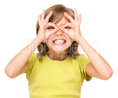 Happy little girl is showing glasses gesture