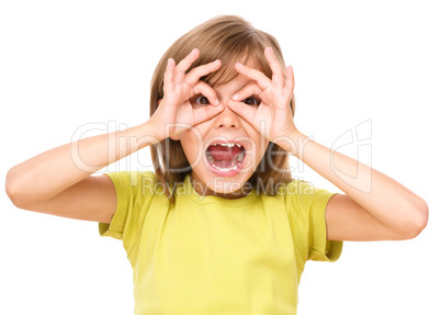 Happy little girl is showing glasses gesture