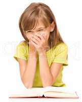 Cheerful young girl is reading book