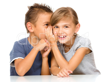 Little girl and boy are whispering in ear