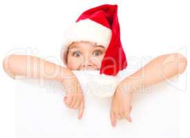Little girl in santa hat is holding blank board