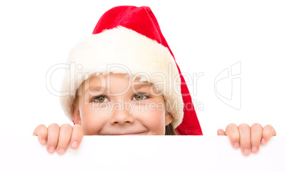 Little girl in santa hat is holding blank board