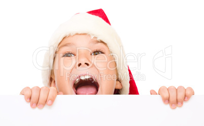 Little girl in santa hat is holding blank board