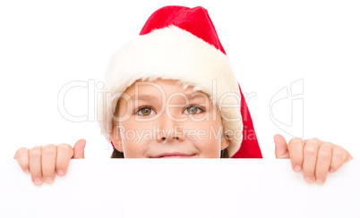 Little girl in santa hat is holding blank board