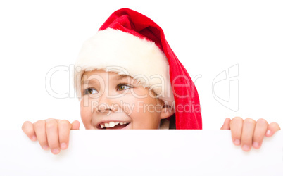 Little girl in santa hat is holding blank board