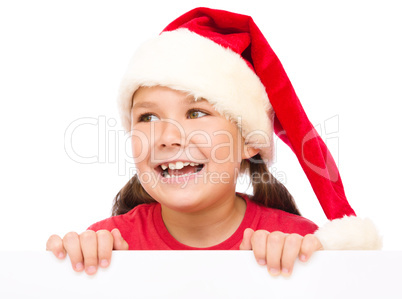 Little girl in santa hat is holding blank board