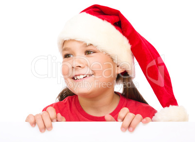 Little girl in santa hat is holding blank board