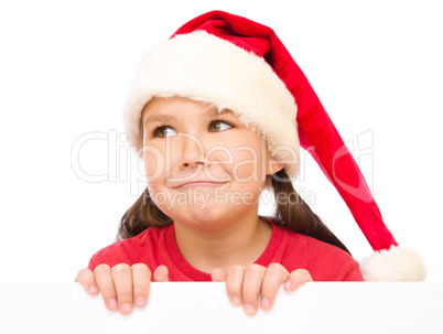 Little girl in santa hat is holding blank board