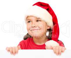 Little girl in santa hat is holding blank board