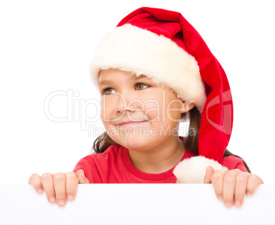 Little girl in santa hat is holding blank board