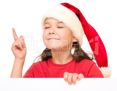 Little girl in santa hat is holding blank board