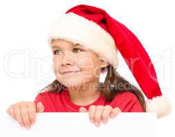 Little girl in santa hat is holding blank board