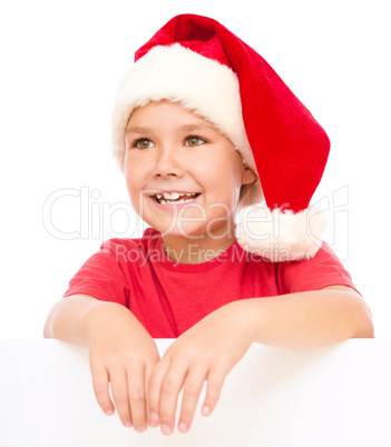 Little girl in santa hat is holding blank board