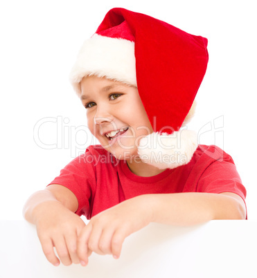 Little girl in santa hat is holding blank board