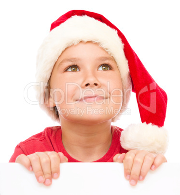 Little girl in santa hat is holding blank board