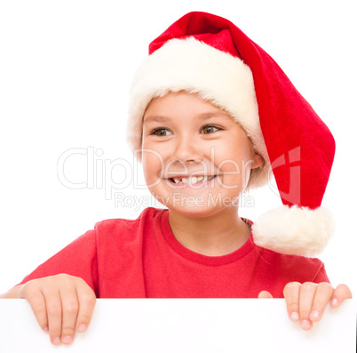 Little girl in santa hat is holding blank board